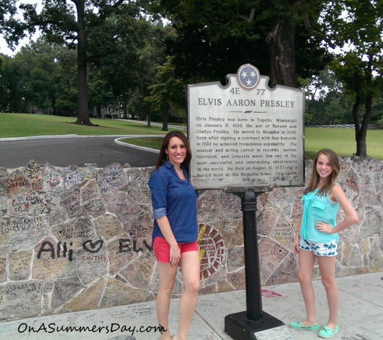 Two women stand in front of a sign that reads "Elvis Aaron Presley"