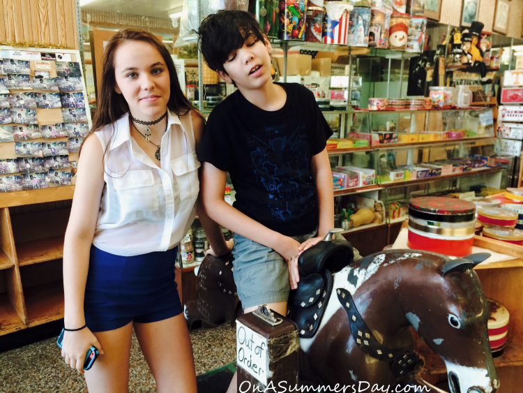 Girl stands next to a boy who is riding a toy horse